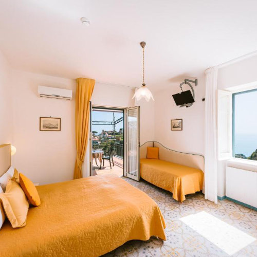 Chambre lumineuse aux tons jaunes avec balcon vue mer à l'Hôtel Villa Giuseppina.
