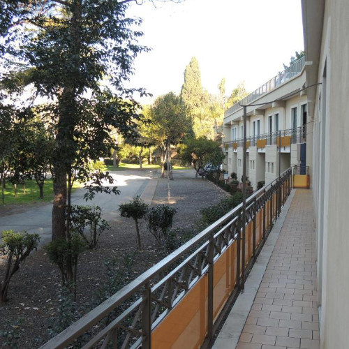Long balcon extérieur de l'Hôtel Zeus offrant une vue sur le jardin.