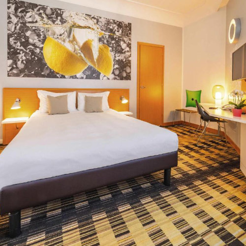 Chambre double lumineuse avec une décoration "pop" sur le thème des agrumes et une moquette graphique jaune et noire.