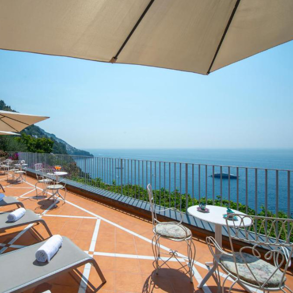 Terrasse de l’Hotel Il Barilotto à Positano avec transats, parasols et vue sur la mer.