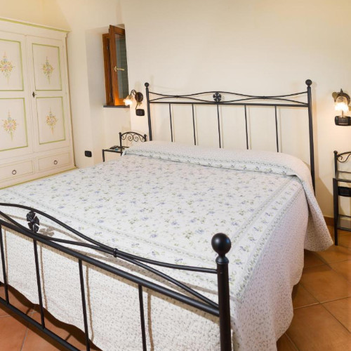 Chambre classique de l'établissement Il Glicine avec lit en fer forgé et mobilier traditionnel.