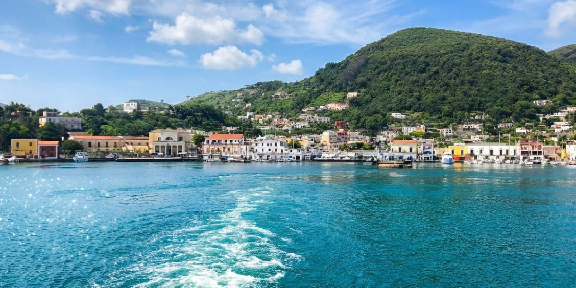 Vue du port d'Ischia Porto et de ses collines verdoyantes depuis un bateau.