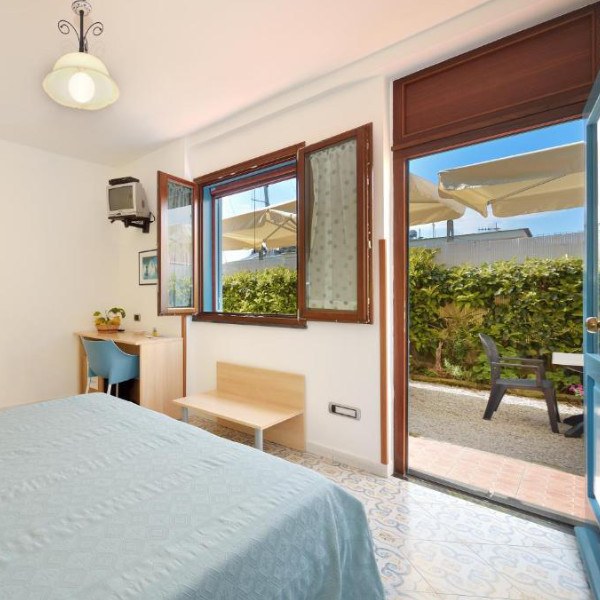 Chambre lumineuse avec carrelage traditionnel, s'ouvrant sur une petite cour intérieure.