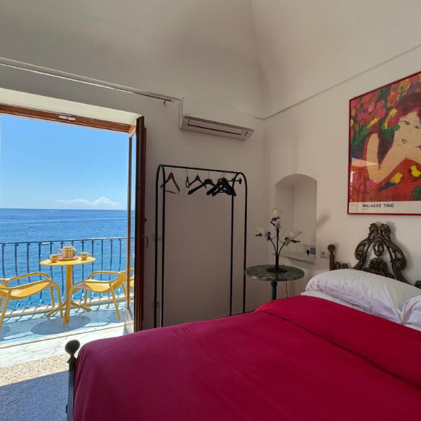 Chambre de La Dolce Vita à Positano avec balcon ouvert sur la mer.
