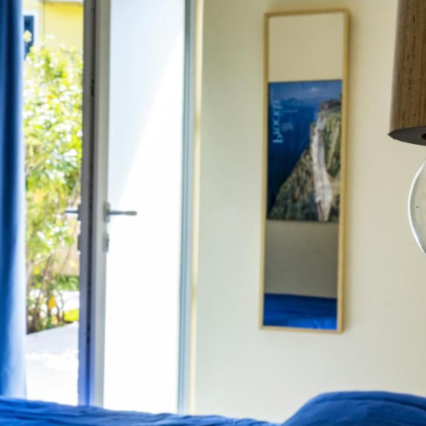 Intérieur épuré d'une chambre lumineuse avec une porte ouverte sur l'extérieur ensoleillé.