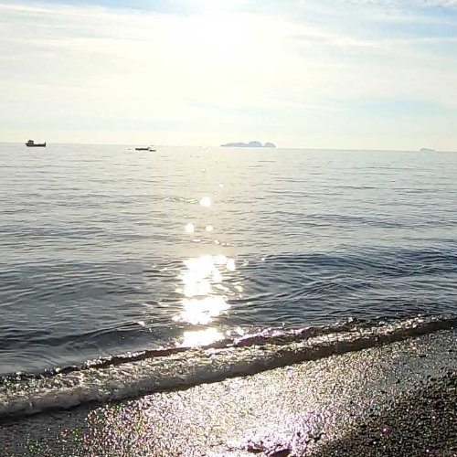 Mer calme face aux îlots Li Galli à Positano avec reflets du soleil sur l’eau.