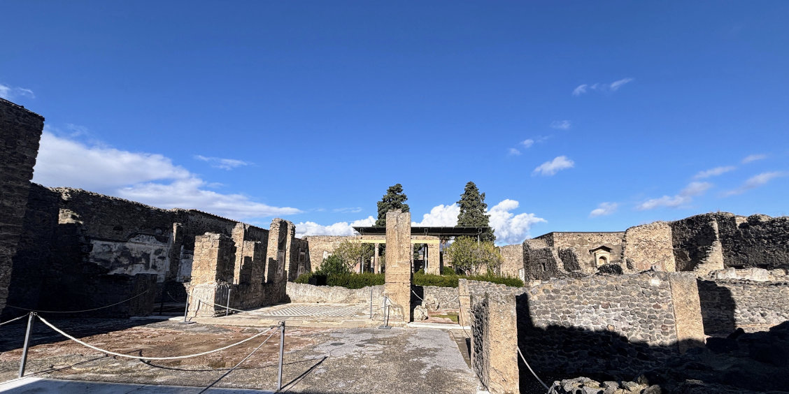 Vue d'ensemble des ruines de la Maison du Faune à Pompéi sous un ciel bleu.