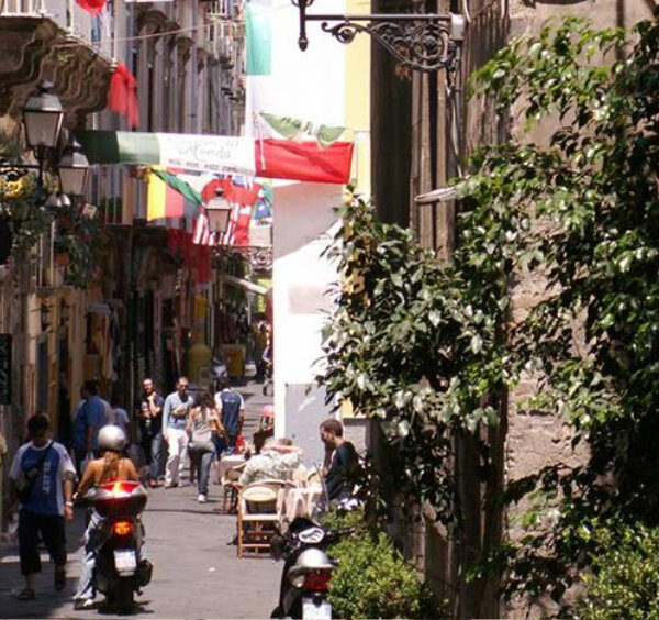 Scooter dans une ruelle du centre de Sorrente avec boutiques, passants et végétation.