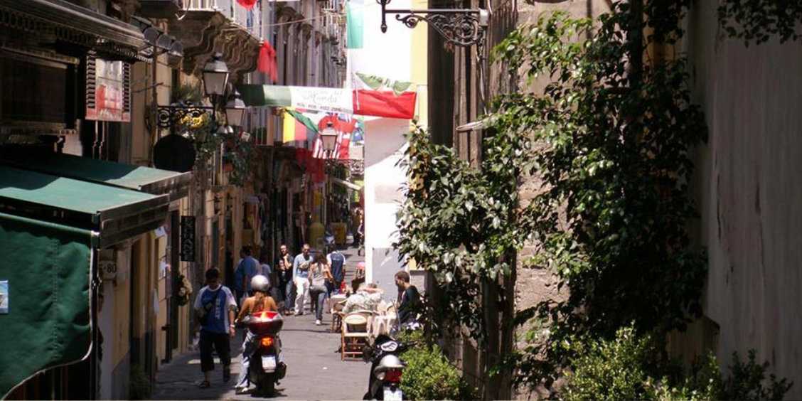 Scooter dans une ruelle du centre de Sorrente avec boutiques, passants et végétation.