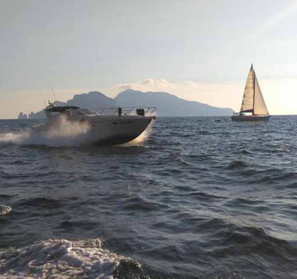 Yacht au large de Sorrente avec mer brillante et Capri à l’horizon.