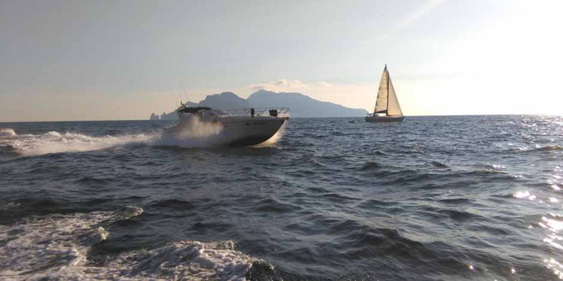 Yacht au large de Sorrente avec mer brillante et Capri à l’horizon.