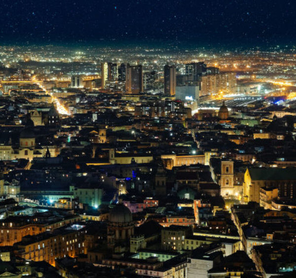 Vue nocturne de Naples avec centre historique illuminé et panorama urbain sur la ville.