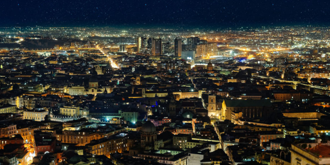 Vue nocturne de Naples avec centre historique illuminé et panorama urbain sur la ville.