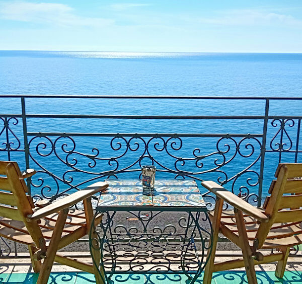 Balcon privé avec chaises en bois et table en céramique face à la mer à Maiori.