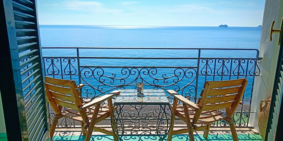 Balcon privé avec chaises en bois et table en céramique face à la mer à Maiori.