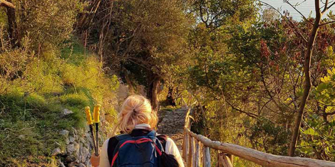 Sentier de randonnée à Pogerola avec une marcheuse au milieu de la végétation.