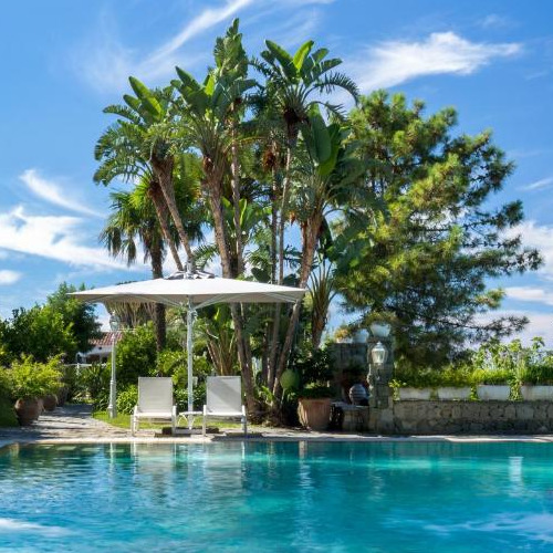 Piscine étincelante entourée de végétation tropicale avec chaises longues au Luxury Relais Villa Magdalena.