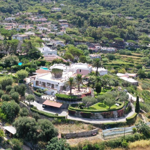 Vue aérienne de la structure blanche et des jardins luxuriants du Luxury Relais Villa Magdalena sur les collines d'Ischia.