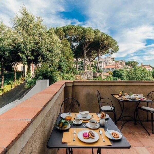 Terrasse du Maera B&B à Ravello avec tables de petit-déjeuner et vue sur les jardins.