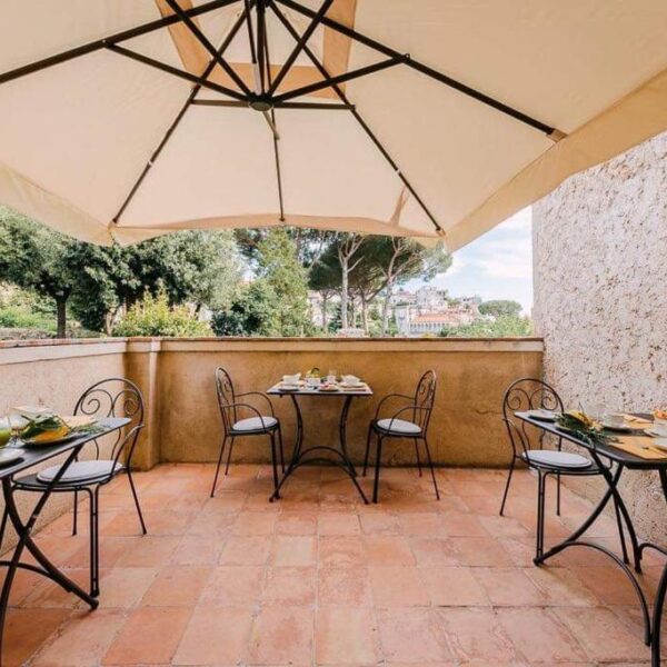 Terrasse ombragée du Maera B&B à Ravello avec tables dressées pour le petit-déjeuner.