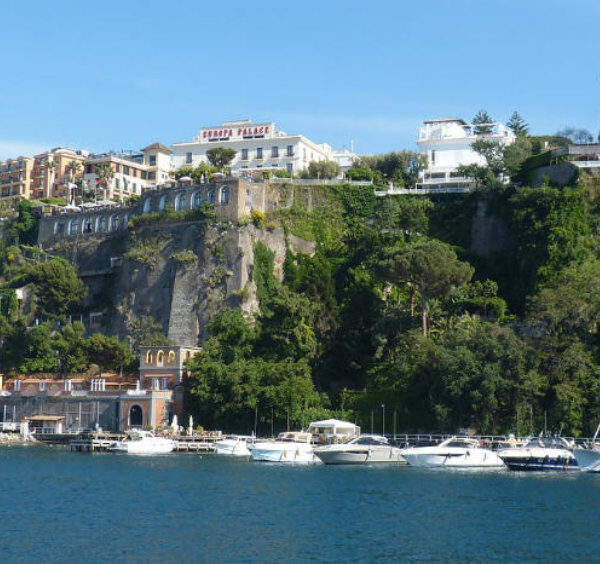 Port de Sorrente en mai avec bateaux amarrés, falaises verdoyantes et hôtels panoramiques.