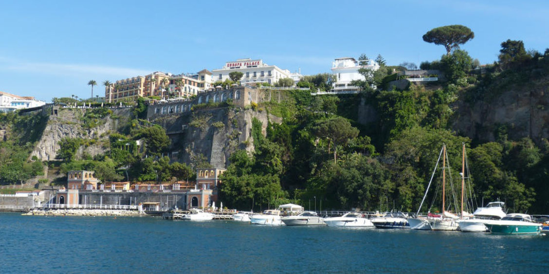 Port de Sorrente en mai avec bateaux amarrés, falaises verdoyantes et hôtels panoramiques.