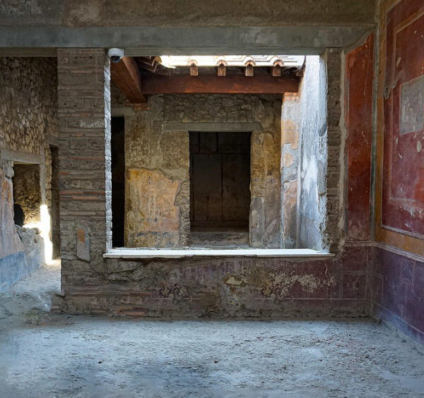 Intérieur d'une maison privée à Pompéi avec des fresques murales colorées et des vues sur les pièces adjacentes.