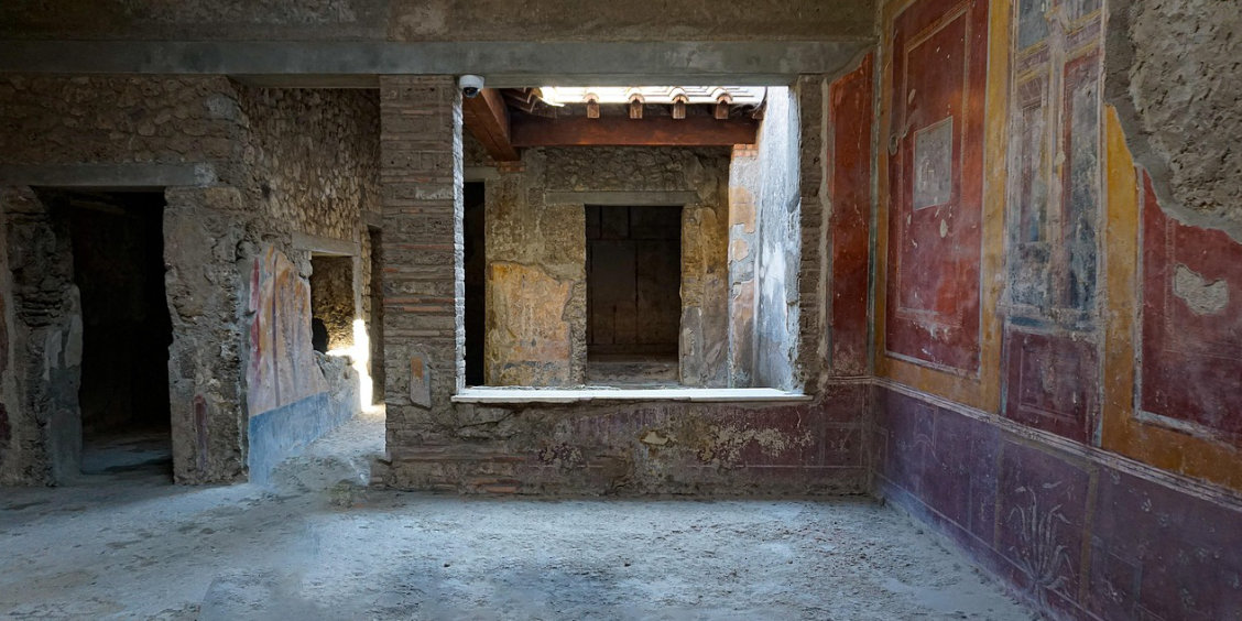 Intérieur d'une maison privée à Pompéi avec des fresques murales colorées et des vues sur les pièces adjacentes.