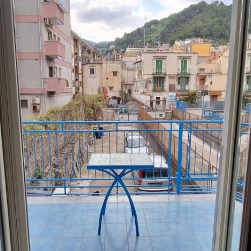 Balcon avec table bleue et vue sur les bâtiments et les collines verdoyantes de Maiori.