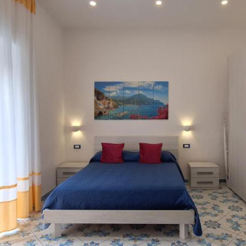 Chambre confortable avec carrelage décoré, lit bleu et tableau de la côte à Mamma Giovanna.
