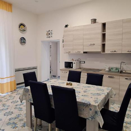 Cuisine moderne et coin repas avec table pour six personnes et sol en faïence bleue.