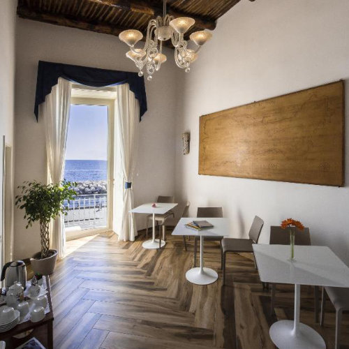 Salle de petit-déjeuner de Mareluna Suite de Charme avec vue sur mer et plafond en bois à Naples.