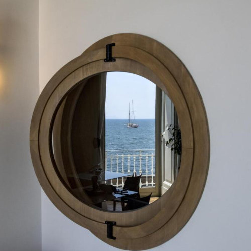 Hublot décoratif reflétant un voilier sur la mer dans une chambre d'hôtes de luxe à Naples.