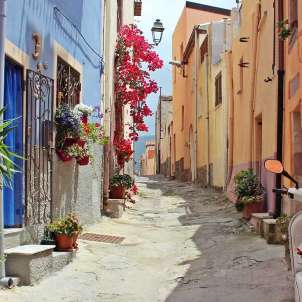 Ruelle typique de Marina Chiaiolella à Procida, Campanie, ornée de fleurs et d'un scooter blanc traditionnel.