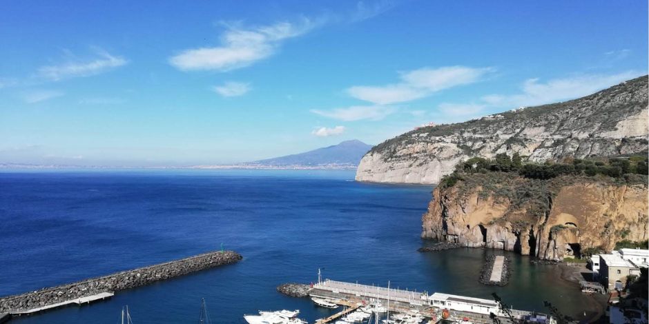 Marina di Cassano à Piano di Sorrento, avec port, falaises et vue sur le Vésuve dans le golfe de Naples.