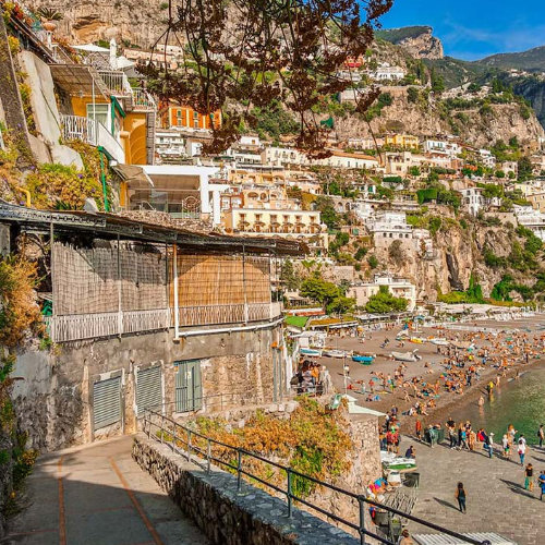 Vue panoramique de la plage de Positano avec ses maisons colorées à flanc de falaise et l'animation sur le front de mer.