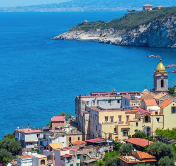 Massa Lubrense vue depuis la côte avec église, maisons et mer bleue.