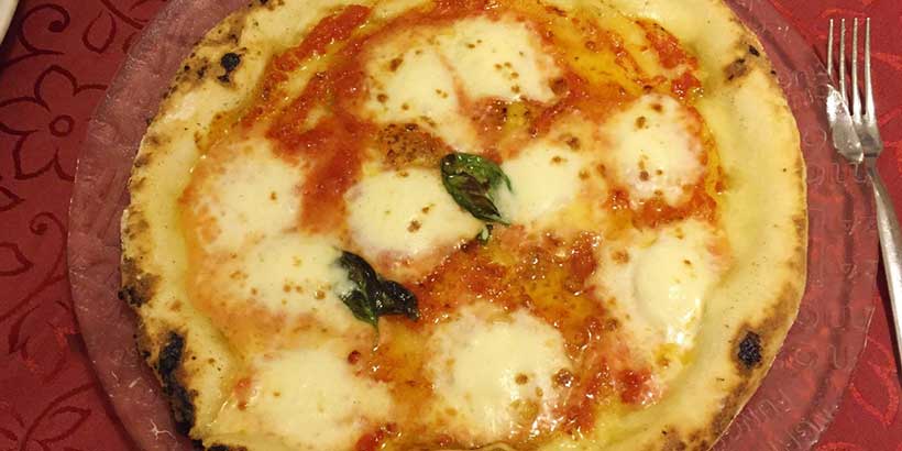 Pizza Margherita napolitaine avec mozzarella fondante, sauce tomate et basilic, spécialité traditionnelle de Naples.