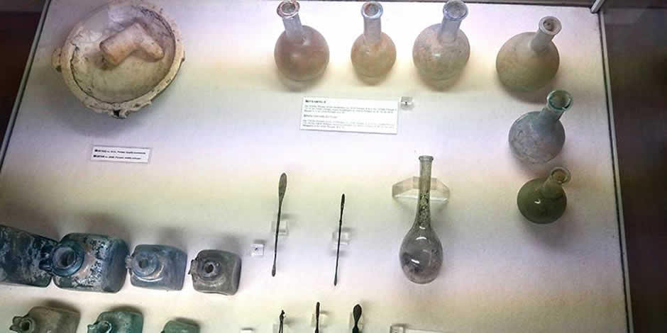 Vitrine de musée exposant des flacons de verre et des outils chirurgicaux de l'époque romaine.