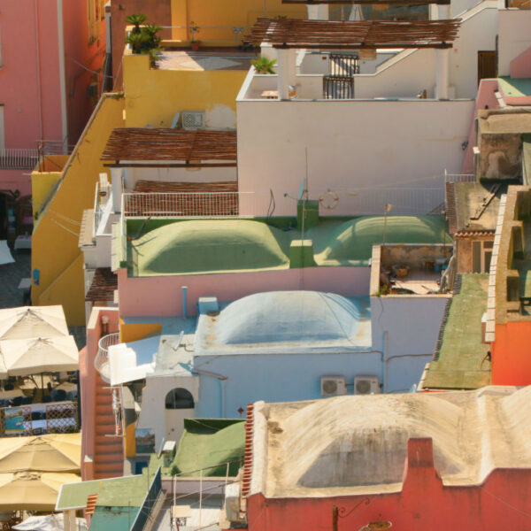Gros plan sur les maisons colorées de Marina Corricella à Procida, Campanie, avec ses bateaux amarrés et parasols de quai.