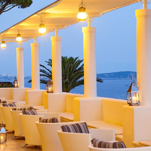 Terrasse illuminée du San Montano Resort & Spa offrant une vue romantique sur la baie au crépuscule.