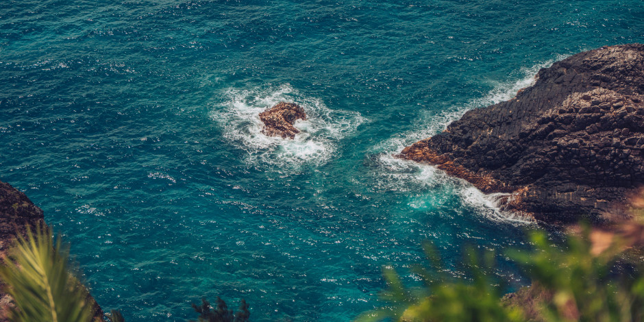 Vagues de la mer turquoise venant s'écraser contre les rochers sombres de la côte de Capri.