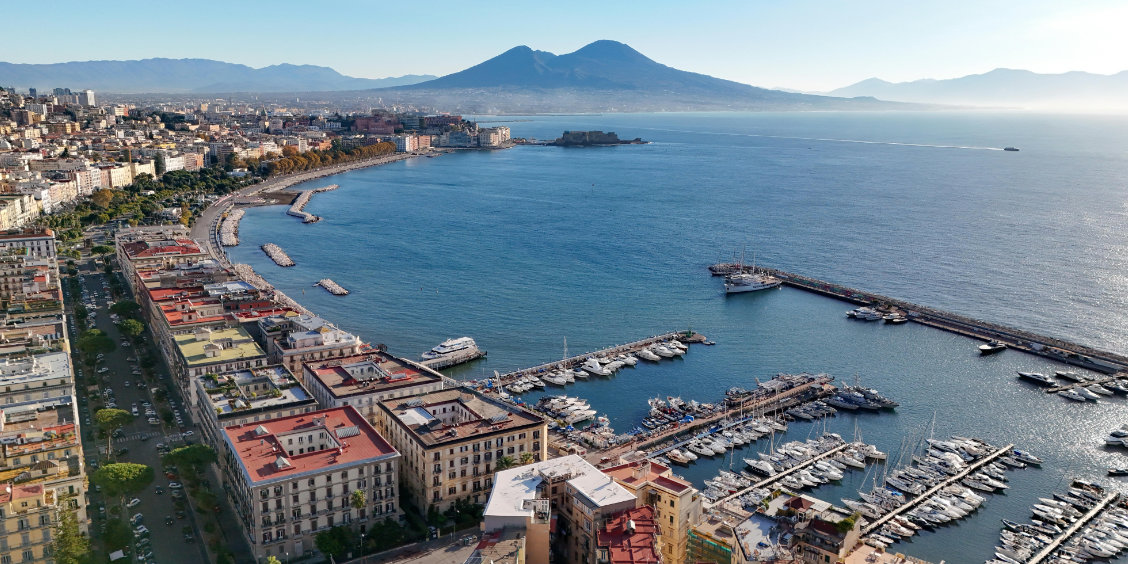 Le port de Mergellina à Naples avec des bateaux et la colline de Posillipo en arrière-plan.