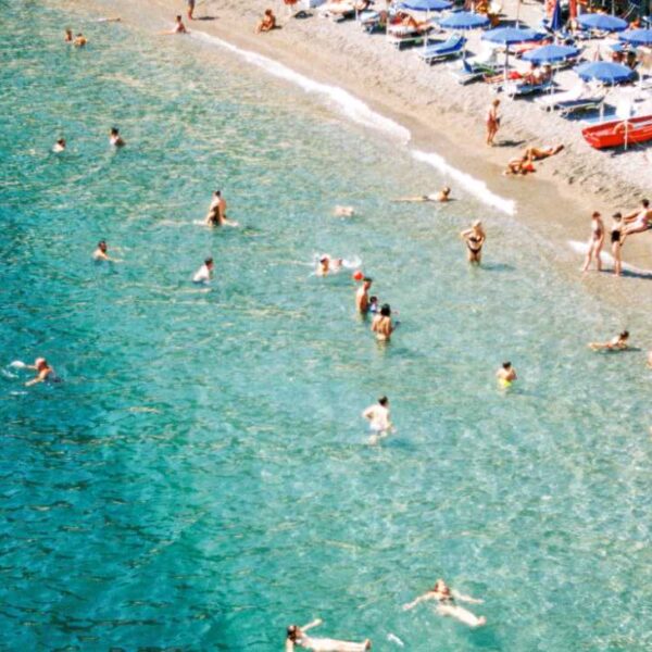 Plage de Minori sur la Côte Amalfitaine, avec eaux turquoise, baigneurs et parasols en bord de mer.
