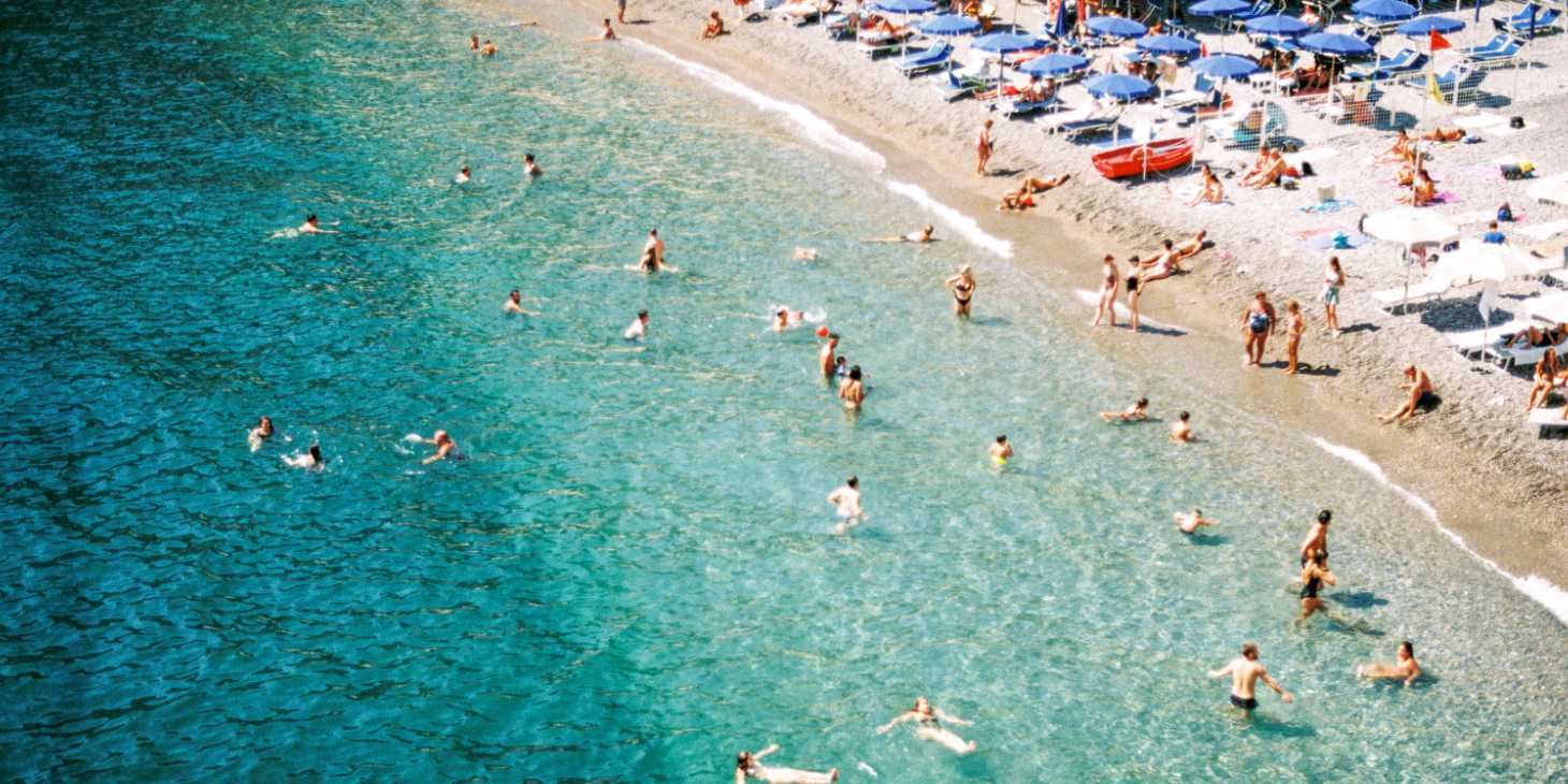 Plage de Minori sur la Côte Amalfitaine, avec eaux turquoise, baigneurs et parasols en bord de mer.