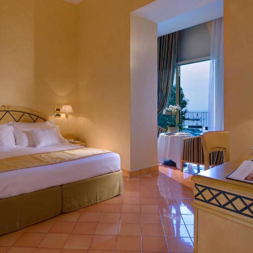 Chambre élégante avec sol en terre cuite et balcon face à la mer.