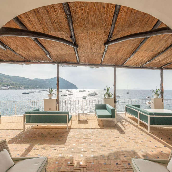 Terrasse lounge ombragée avec canapés modernes et vue imprenable sur la baie au Miramare Sea Resort & Spa.