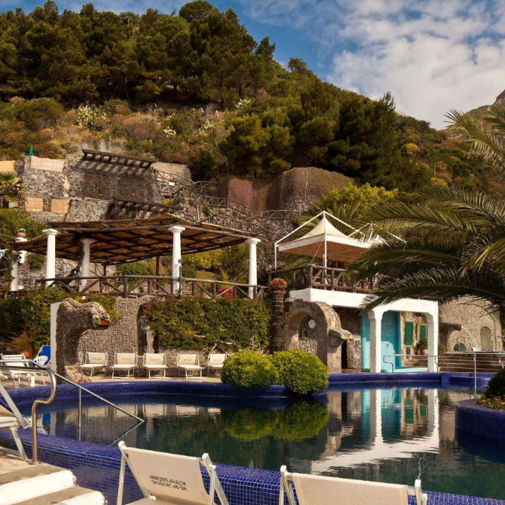 Piscine extérieure azur entourée de jardins et de structures méditerranéennes au Miramare Sea Resort & Spa.