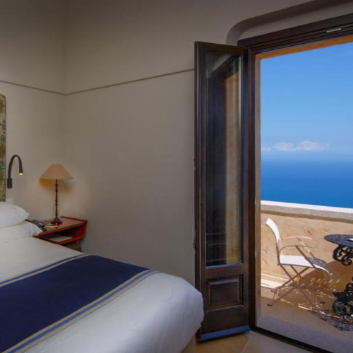 Chambre de luxe avec balcon privé ouvrant sur une vue imprenable sur la mer.