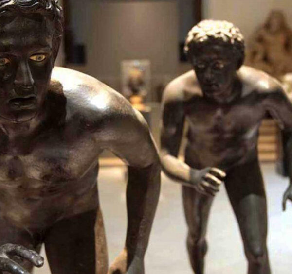 Deux célèbres sculptures en bronze antiques de coureurs exposées dans une salle du MANN.